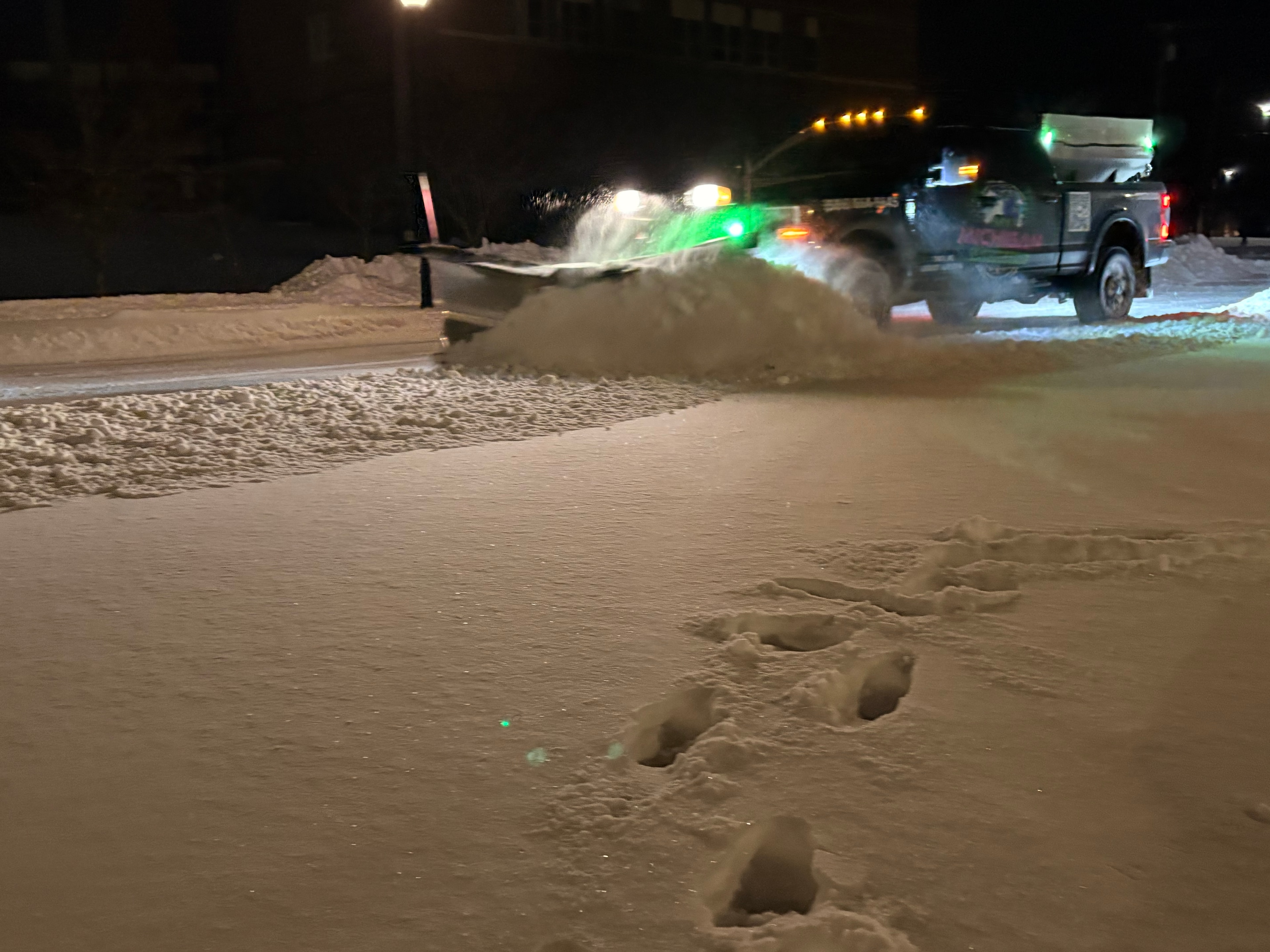 Commercial snow plow truck clearing a winter parking lot